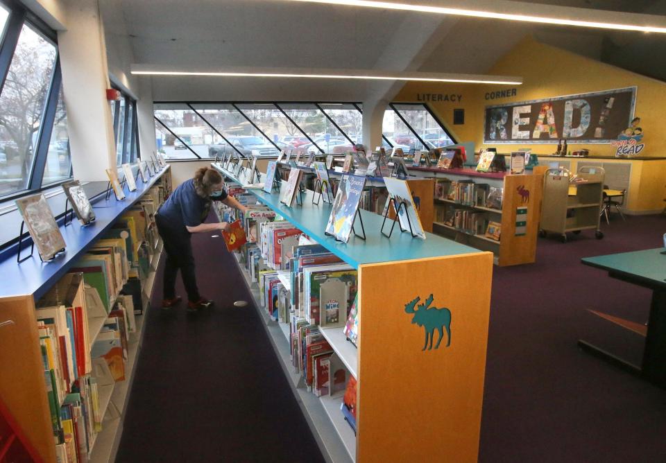 Sondra Easterly returns books to shelves in the children's section of the Stark Library main branch in Canton in this file photo from December 2021.