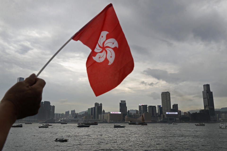 A supporter raises a Hong Kong flag against Victoria Harbor during a counter-rally in support of the police in Hong Kong Saturday, July 20, 2019. Police in Hong Kong have raided a homemade-explosives manufacturing lab ahead of another weekend of protests in the semi-autonomous Chinese territory. (AP Photo/Vincent Yu)