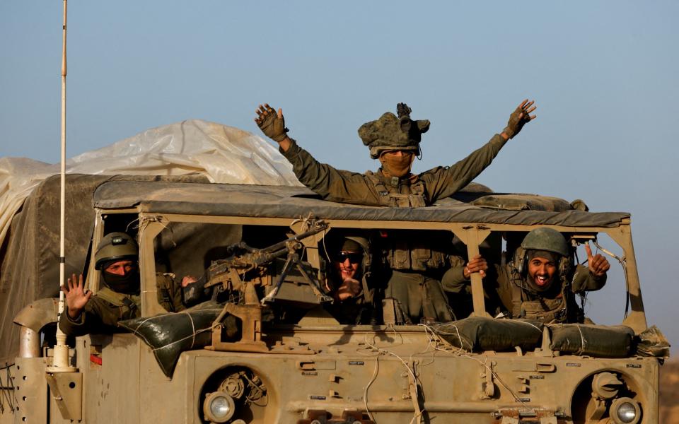 Israeli soldiers react from a military vehicle while driving by Israel's border