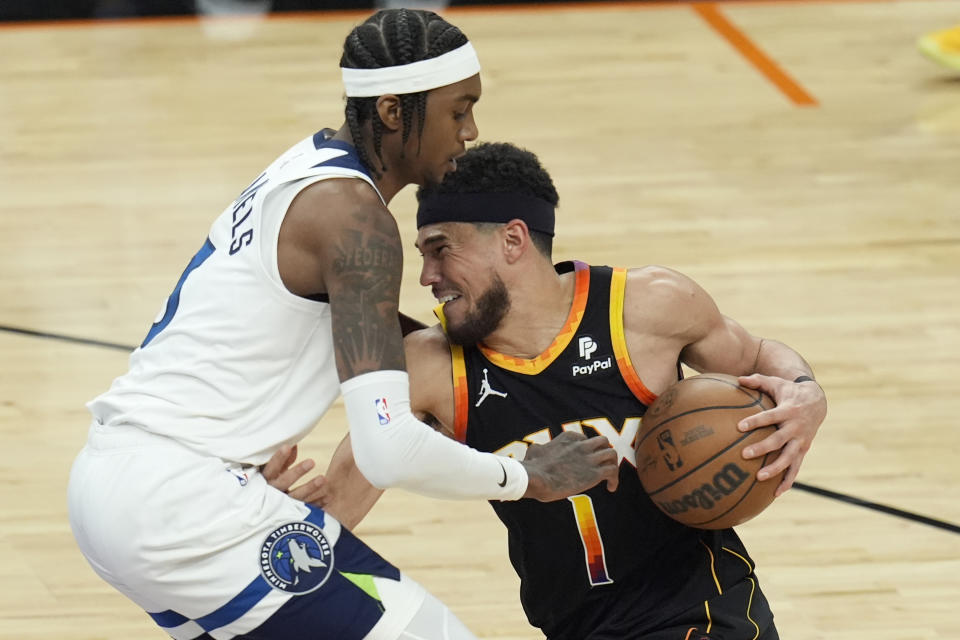 Phoenix Suns guard Devin Booker (1) tries to get past Minnesota Timberwolves forward Jaden McDaniels, left, during the second half of Game 4 of an NBA basketball first-round playoff series Sunday, April 28, 2024, in Phoenix. The Timberwolves won 122-116, taking the series 4-0. (AP Photo/Ross D. Franklin)