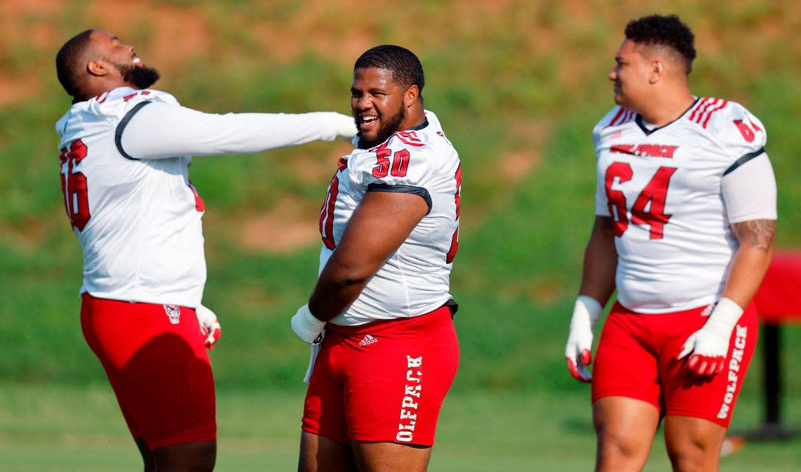 From left N.C. State’s Bryson Speas (56), Grant Gibson (50) and Chandler Zavala (64) share a laugh at the start of the Wolfpack’s first practice of fall camp in Raleigh, N.C., Wednesday, August 3, 2022.