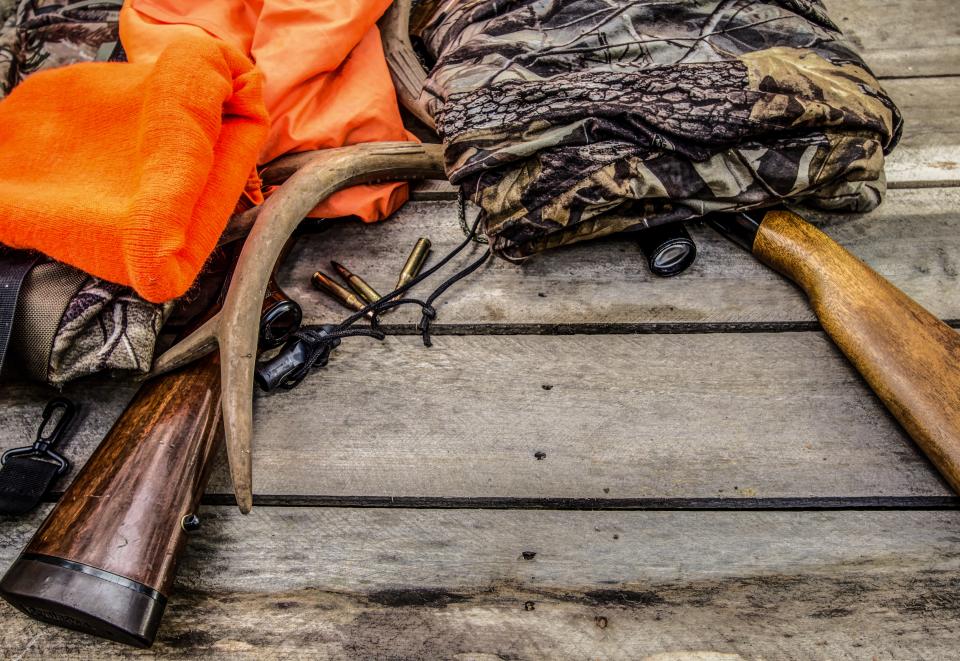 Deer hunting background with hunting gear and apparel on a rustic wooden background.