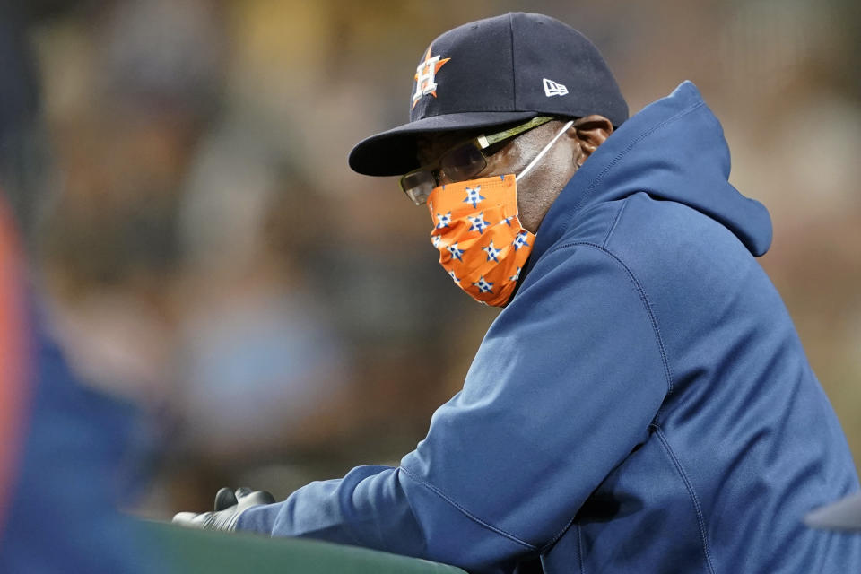 Houston Astros manager Dusty Baker Jr. wears a mask as he looks out from the dugout rail during a baseball game against the Seattle Mariners, Monday, July 26, 2021, in Seattle. (AP Photo/Ted S. Warren)