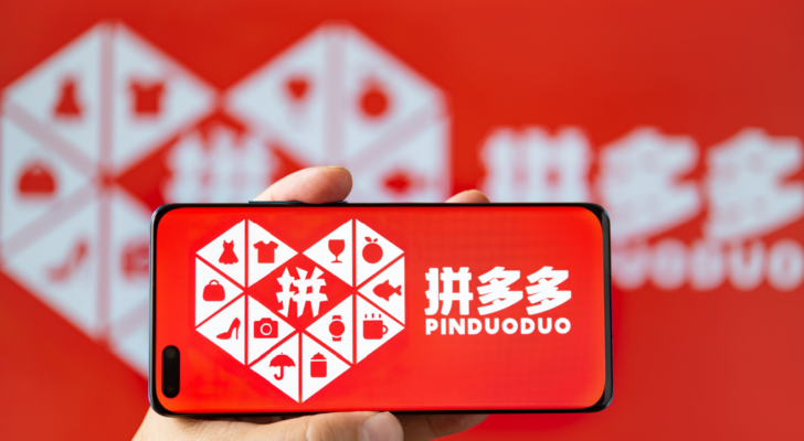 Man holding a mobile with PinDuoDuo (PDD) logo at horizontal composition.