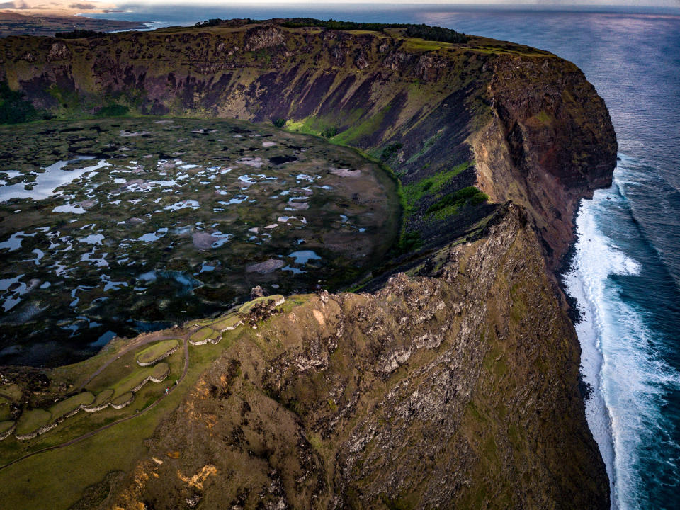 Niños juegan en el océano detrás de Ahu Tongariki, en la Isla de Pascua. (Josh Haner/The New York Times)