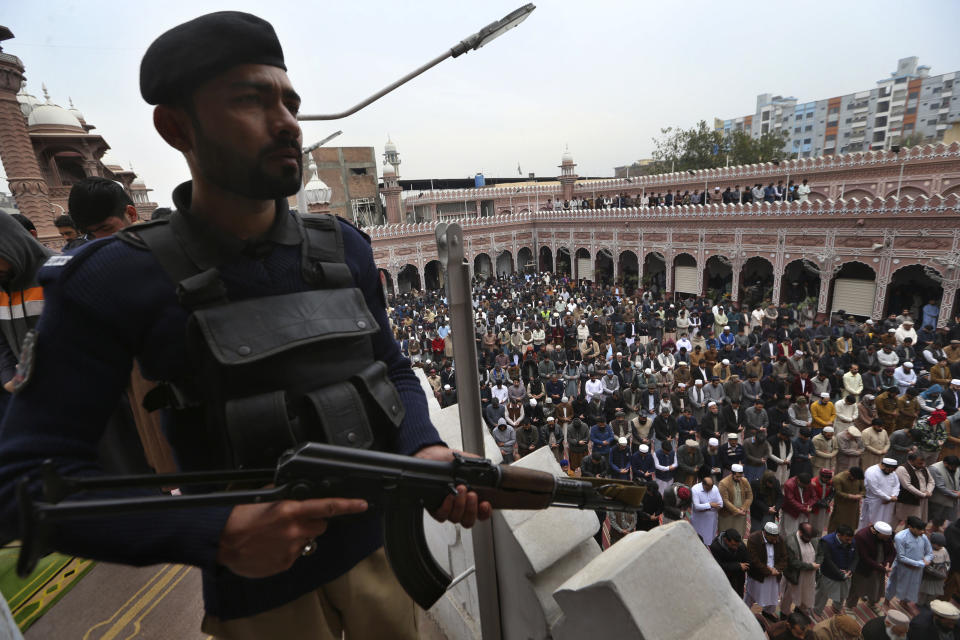 A police officer stands guard as people take part in Friday prayers at a mosque, in Peshawar, Pakistan, Friday, Feb. 3, 2023. (AP Photo/Muhammad Sajjad)