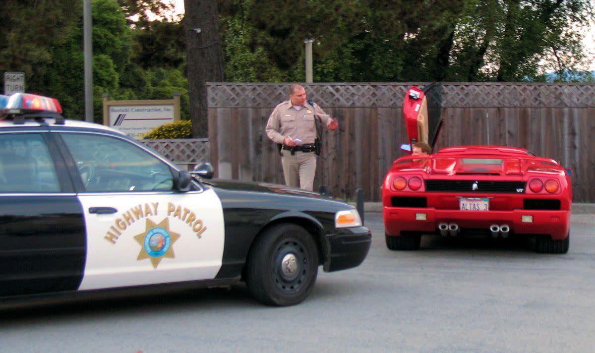 Police officer walking away from a red Lamborghini