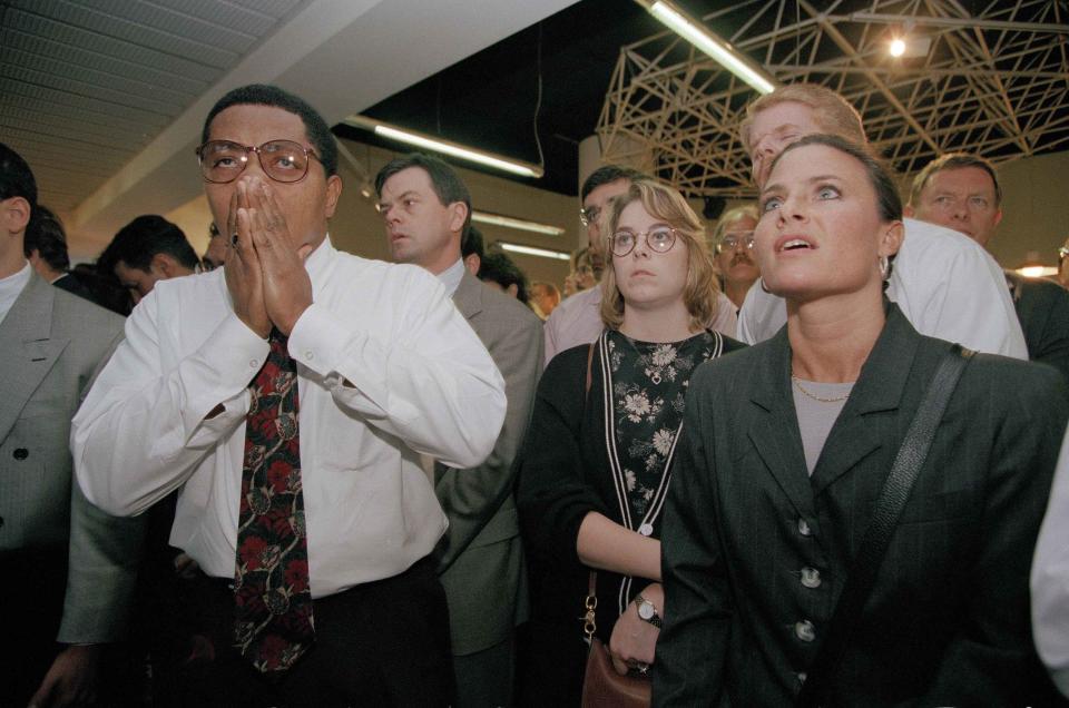 FILE - Christopher Odle, 36, a legal clerk from Crown Heights, Brooklyn, borough of New York, left, wipes away tears moments after hearing the news that O.J. Simpson was found not guilty of killing Nicole Brown Simpson and Ronald Goldman, in New York, Oct. 3, 1995. At right is Bernadette B. Incerto, 33. For many people old enough to remember O.J. Simpson's murder trial, his 1994 exoneration was a defining moment in their understanding of race, policing and justice. Nearly three decades later, it still reflects the different realities of white and Black Americans. (AP Photo/Clark Jones)