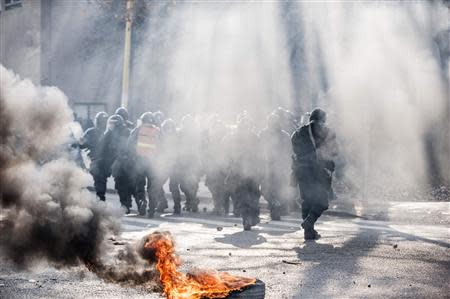 Smoke rises near the police as anti-government protesters hold a demonstration in Tuzla February 6, 2014. REUTERS/STRINGER