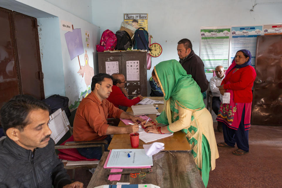 A voter signs a voting register before casting her ballot in a bypoll for an assembly seat in Dharmsala, India, Monday, Oct. 21, 2019. The seat was vacated by Kishan Kapoor, a Bharatiya Janata Party member of legislative assembly , who was elected to the Lok Sabha in May as Voting is underway in two Indian states of Maharashtra in the west and Haryana in the north where the Hindu nationalist Bharatiya Janata Party (BJP) headed by prime minister Narendra Modi is trying to win a second consecutive term. (AP Photo/Ashwini Bhatia)