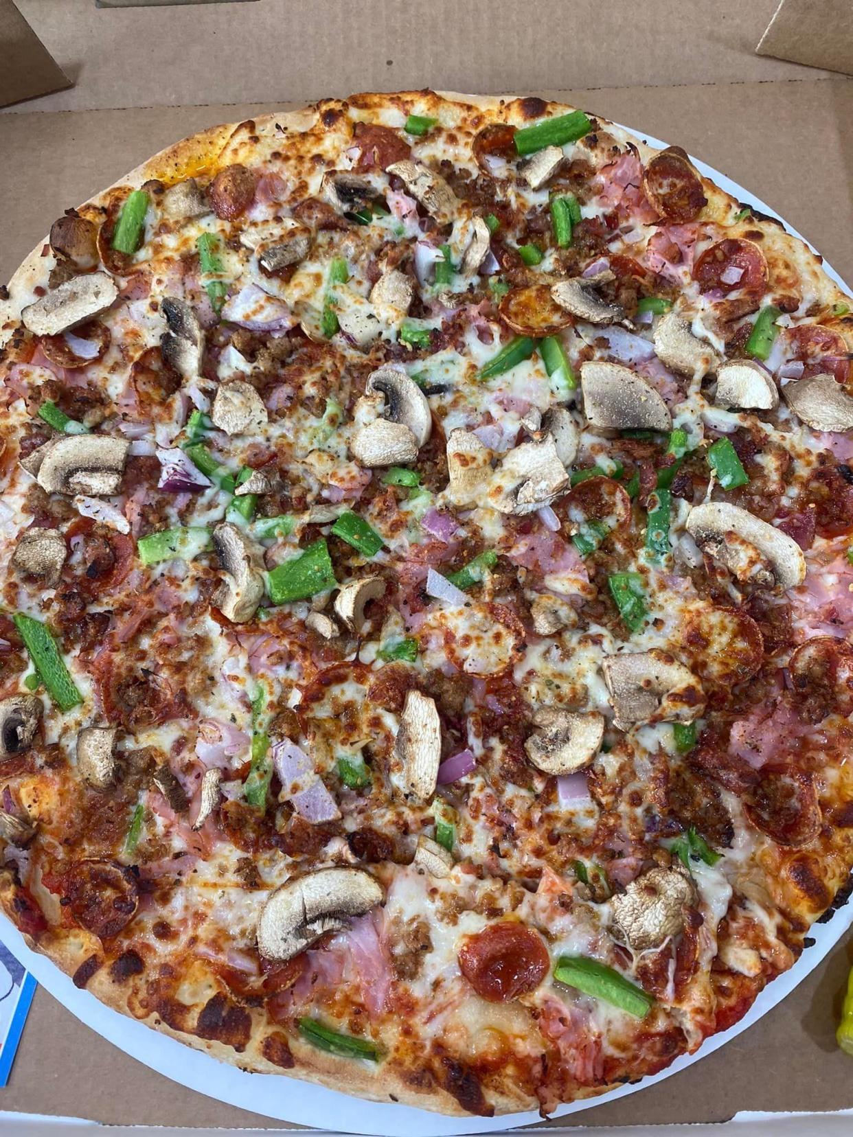 The Graham Slam pizza at Casey's Dugout is loaded with sausage, pepperoni, beef, ham, bacon, onions, green peppers, black olives, mushrooms, and pepperoncini. The crust is thicker than the typical Evansville Una-style crust and the pizza is cut into triangles.
