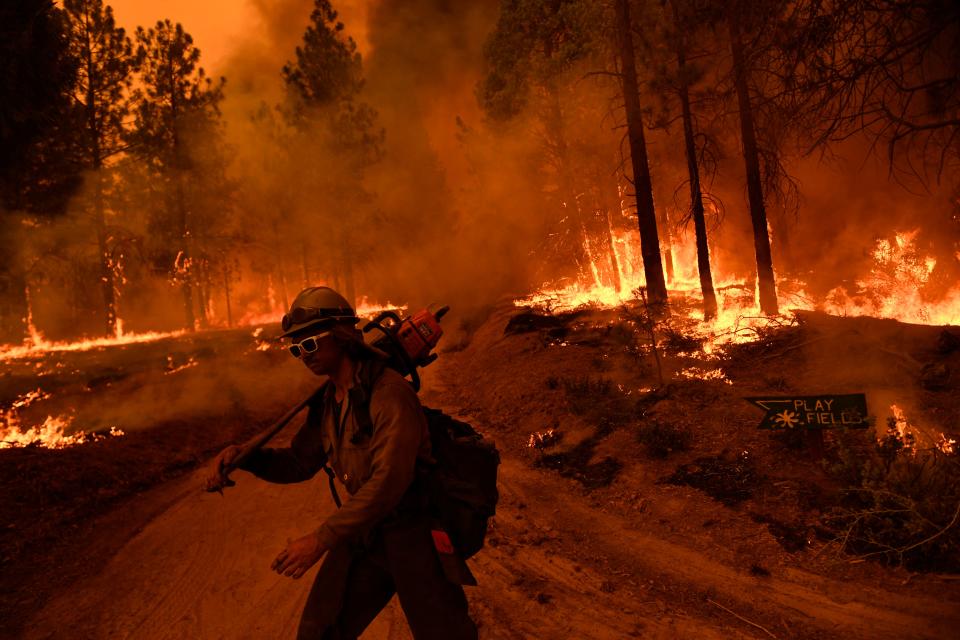 TOPSHOT - A firefighter with Alaska's Pioneer Peak Interagency Hotshot Crew carries a chain saw as the Windy Fire burns in the Sequoia National Forest near Johnsondale, California on September 22, 2021. (Photo by Patrick T. FALLON / AFP) (Photo by PATRICK T. FALLON/AFP via Getty Images)