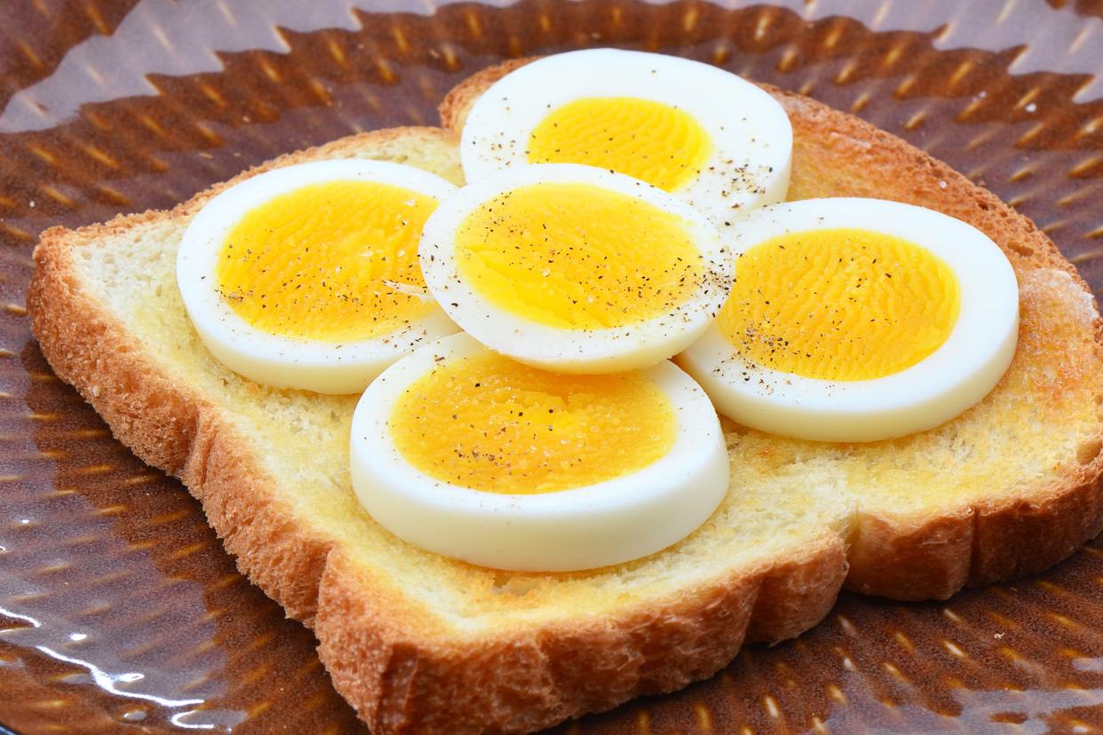 Focus on hard-boiled eggs and toast on a glazed brown ceramic plate