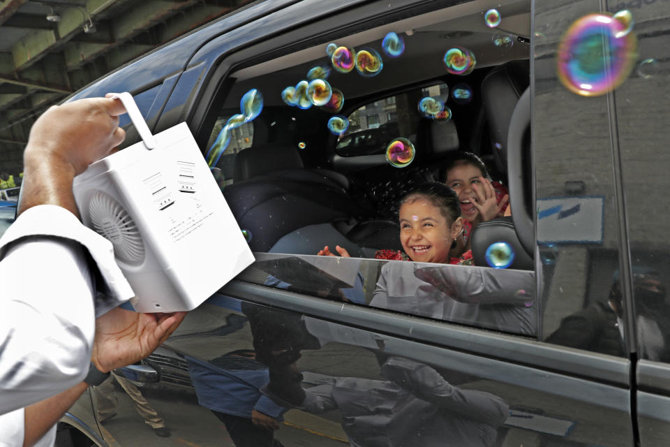 Children react from inside their family's car as a volunteer from the Muslim Community Center blows bubbles at them as part of an Eid al-Fitr celebration, marking the end of the fasting month of Ramadan, in the Sunset Park neighborhood of Brooklyn, Sunday, May 24, 2020, in New York. Due to the need for social distancing because of the coronavirus pandemic, the celebration was held as a drive-thru event in which sweets and toys were handout out. (AP Photo/Kathy Willens)