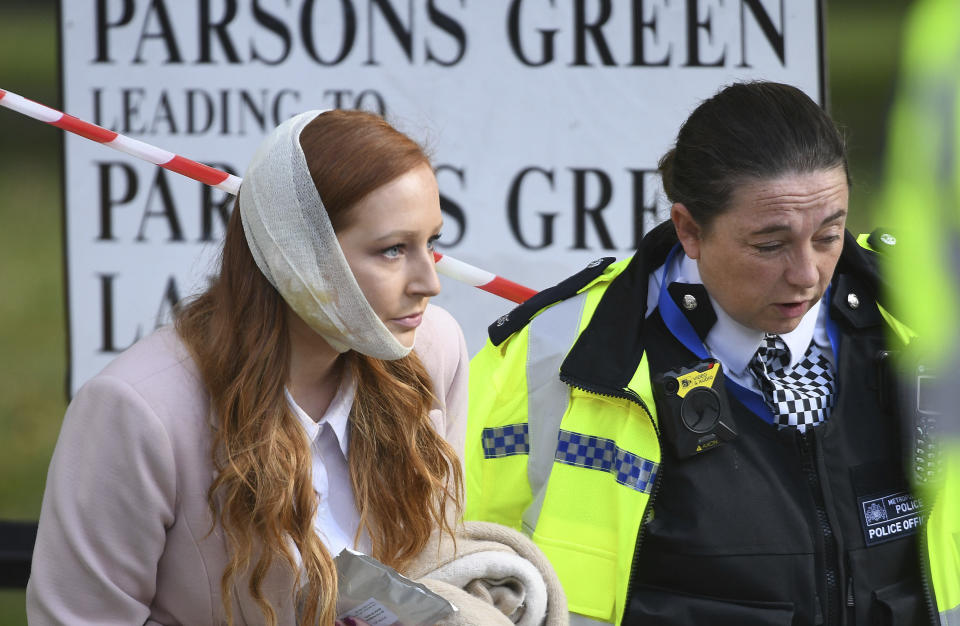 An injured woman being assisted by a police officer close to Parsons Green station after this morning's blast (Stefan Rousseau/PA via AP)