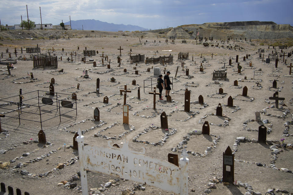 People walk through a historic cemetery in the county seat of Nye County, July 18, 2022, in Tonopah, Nev. The resignation of a county elections clerk in the rural county in Nevada has opened a window on the consequences of unfounded conspiracy theories and raised questions about how local elections will be run when they are overseen by people who don't trust the process. (AP Photo/John Locher)
