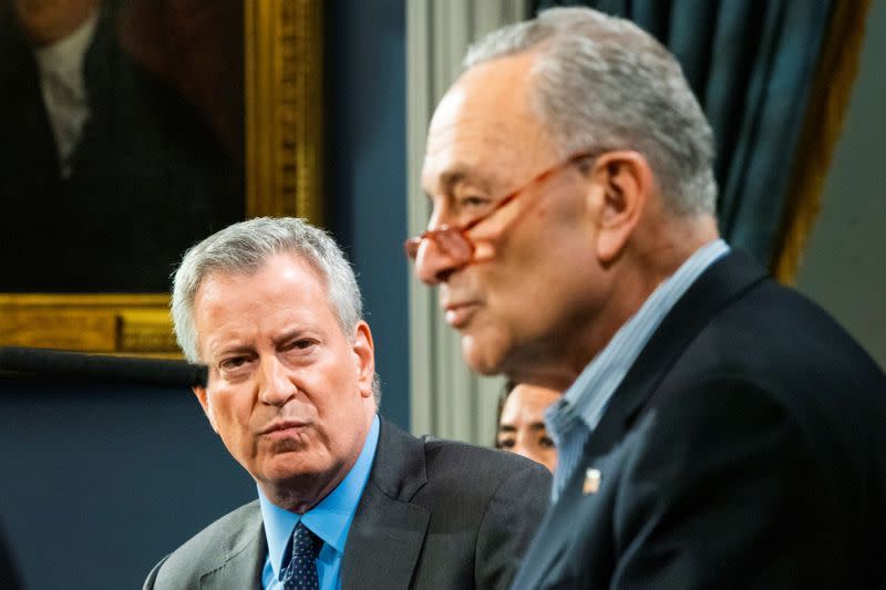 New York City Mayor de Blasio listens to U.S. Senate Minority Leader Schumer, (D-NY) as he speaks during a news briefing of the COVID-19 at the City Hall in the Manhattan borough of New York City, New York