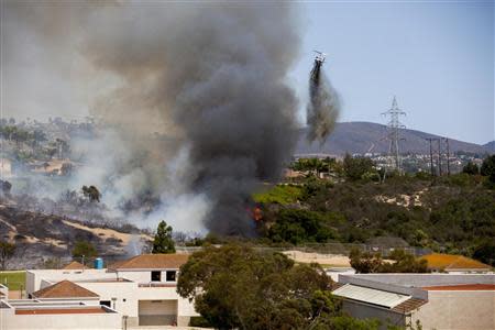 Firefighters in a helicopter drop water on the so-called Poinsettia Fire in Carlsbad, California May 14, 2014. REUTERS/Sam Hodgson