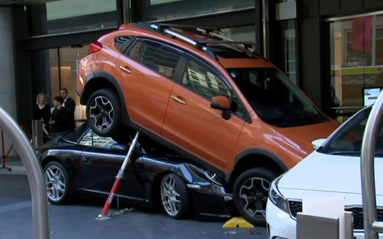 While attempting to park the Porsche, the car reportedly accelerated and ended up under an orange sports utility vehicle (SUV). - Australian Broadcasting Corp.