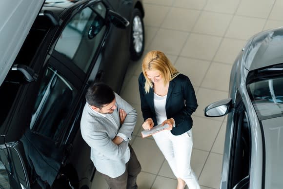 Man talking to woman at car dealership.