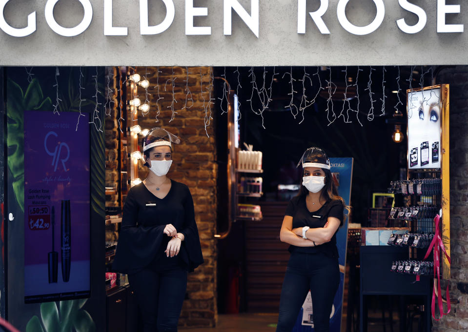 Shop employees, wearing protective masks and face shields against the spread of coronavirus, wait for customers on Istiklal street, the main shopping street in Istanbul, Thursday, June 18, 2020.Turkish authorities have made the wearing of masks mandatory in Istanbul, Ankara and Bursa to curb the spread of COVID-19 following an uptick in confirmed cases since the reopening of many businesses. Masks are now obligatory in all public spaces in 47 out of 81 provinces. (AP Photo/Emrah Gurel)