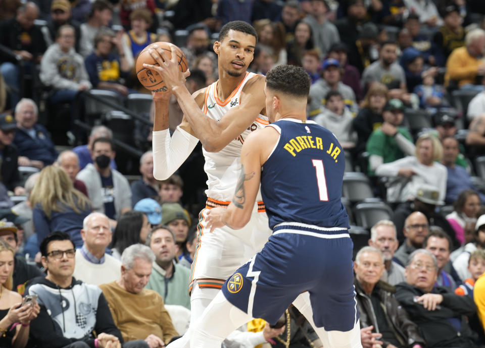 San Antonio Spurs center Victor Wembanyama looks to pass the ball as Denver Nuggets forward Michael Porter Jr. defends in their game Sunday in Denver. (AP Photo/David Zalubowski)