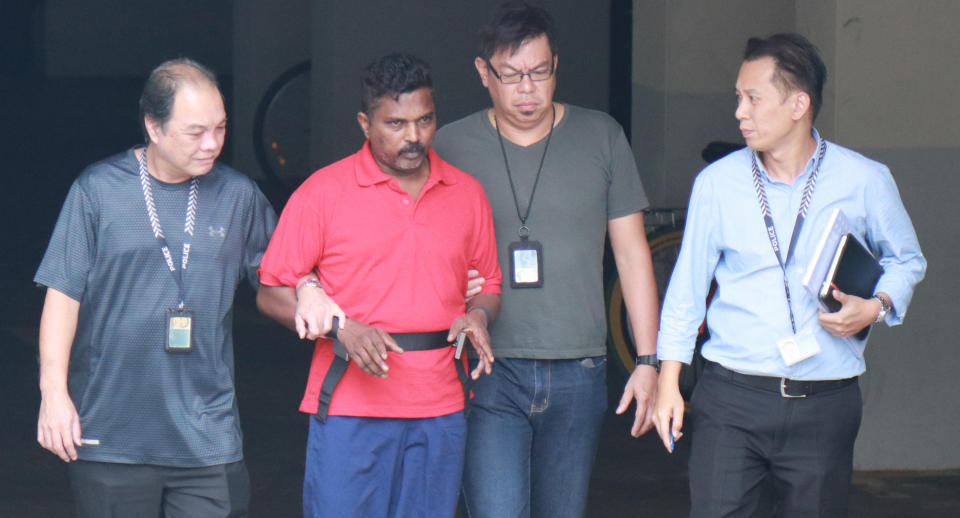 On 1 November 2017, Krishnan Raju (in red) was escorted by officers to the Loyang Gardens condominium on Jalan Loyang Besar where he allegedly killed 44-year-old Raithena Vaithena Samy. Photo: Yahoo News Singapore