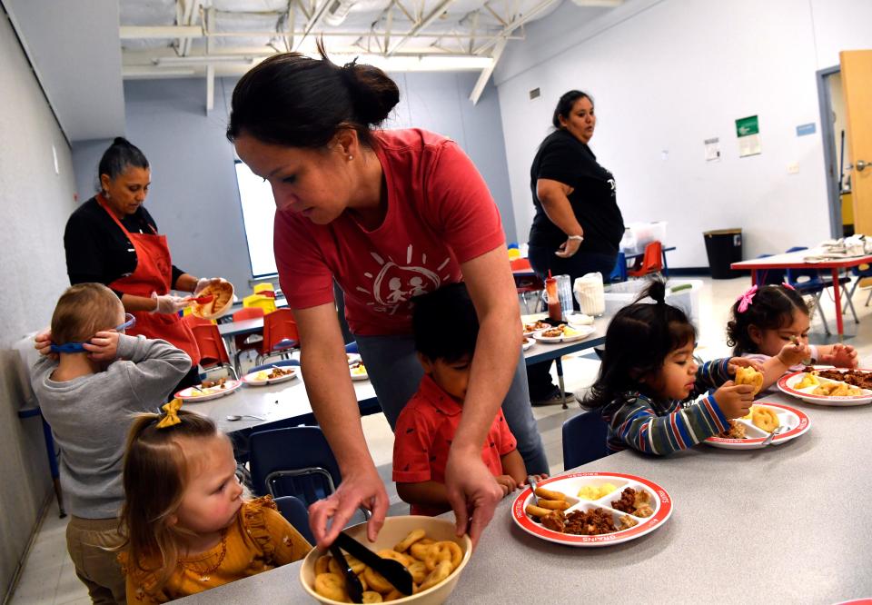 Amanda Gomez, the director at Vine Street Day Nursery, assists children with dishing up their food during lunchtime March 10.