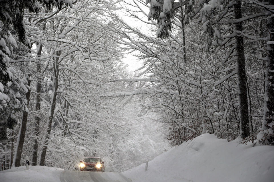 A car drives on a road through a forest in Schongau, southern Germany, Thursday, Jan. 10, 2019 after Austria and southern Germany were hit by heavy snowfall. (Karl-Josef Hildenbrand/dpa via AP)