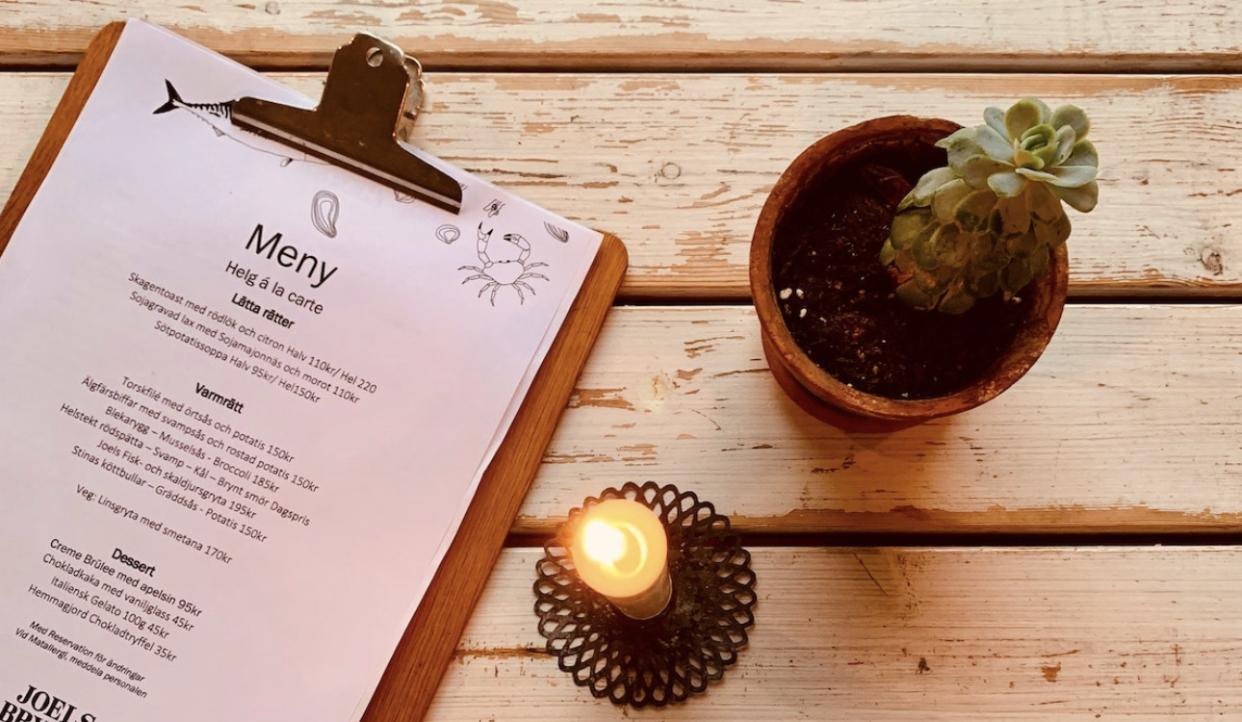 Swedish restaurant menu on table with plant and candle