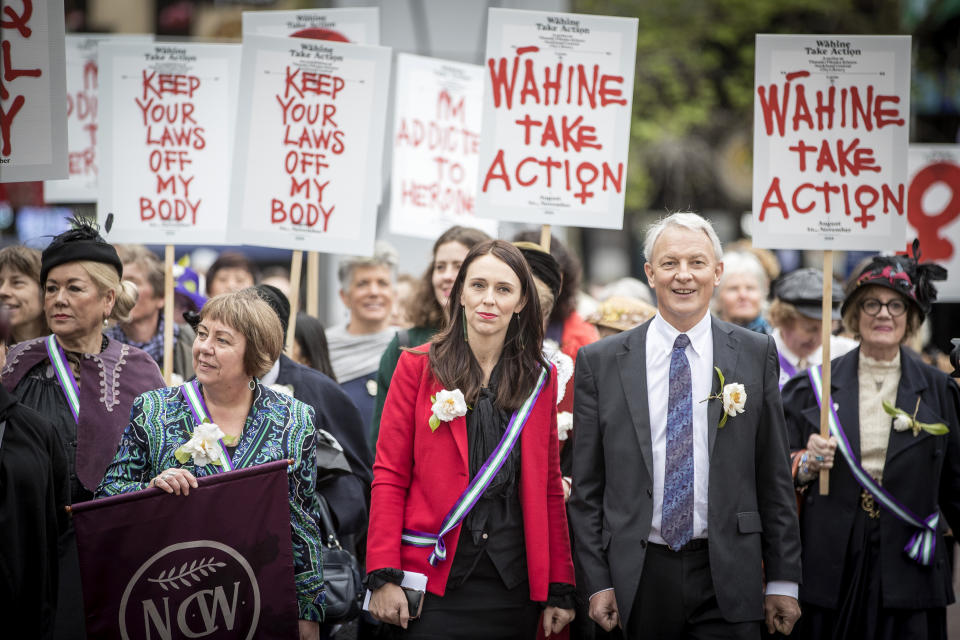 New Zealand Prime Minister Jacinda Ardern, center, and the Mayor of Auckland, Phil Goff attend the Suffrage 125 year sunrise celebration in Auckland, New Zealand, Wednesday, Sept. 19. 2018. New Zealand became the first nation in the world to allow women to vote 125 years ago, and hundreds of people celebrated the anniversary by turning out to gatherings and speeches with some wearing period costumes or the white camellia flowers — a symbol of the movement. (Michael Craig/New Zealand Herald via AP)