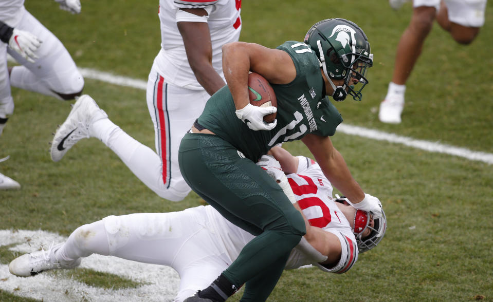 Michigan State running back Connor Heyward (11) stiff arms Ohio State linebacker Pete Werner during the first half of an NCAA college football game, Saturday, Dec. 5, 2020, in East Lansing, Mich. (AP Photo/Al Goldis)