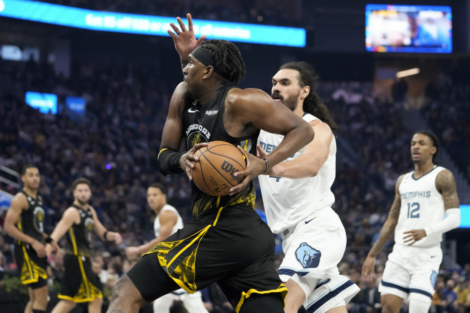 Golden State Warriors forward Kevon Looney, center left, drives to the basket against Memphis Grizzlies center Steven Adams, center right, during the first half of an NBA basketball game in San Francisco, Sunday, Dec. 25, 2022. (AP Photo/Godofredo A. Vásquez)