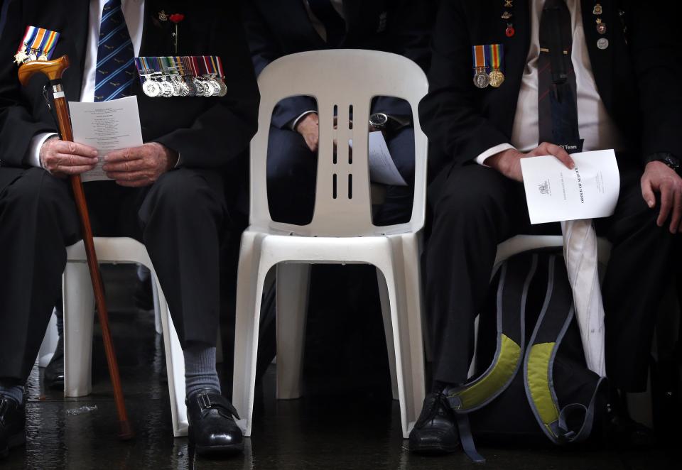 War veterans wearing medals sit next to a vacant chair during a Remembrance Day ceremony in Sydney