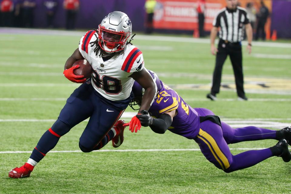 New England's Rhamondre Stevenson tries to break the tackle of Minnesota's Harrison Smith.