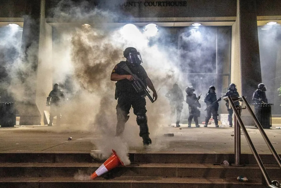 A police officer kicks over a safety cone that protesters placed over a tear gas canister as police in riot gear protect the courthouse during a protest in downtown Raleigh Saturday, May 30, 2020.