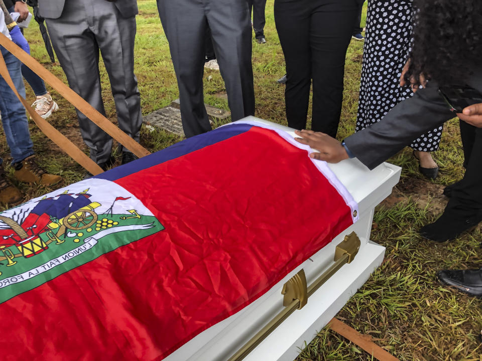 A woman places her hand on the casket of one of 11 Haitian women who died last month when the overloaded boat they were in capsized, in San Juan, Puerto Rico, Wednesday, June 15, 2022. The boat was carrying an estimated 60 to 75 migrants, of which eleven were found dead, at least a dozen still missing and 38 rescued. (AP Photo/Dánica Coto)
