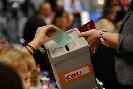 A delegate holds a voting card with "Yes" for Angela Merkel to elect the leader of the conservative Christian Democratic Union party CDU during a party convention in Essen, Germany, December 6, 2016. REUTERS/Wolfgang Rattay