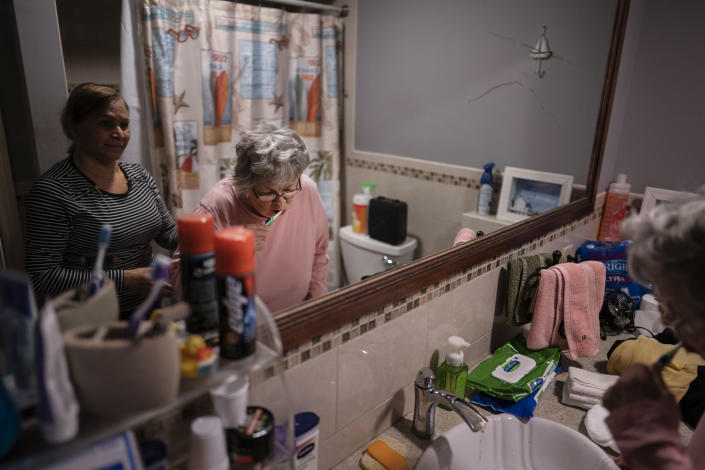 Arelis Estrella, left, a nursing assistant, watches as Betty Bednarowski brushes her teeth in the morning as part of their out-of-bed routine, Tuesday, Nov. 30, 2021, in Rotterdam Junction, N.Y. (AP Photo/Wong Maye-E)