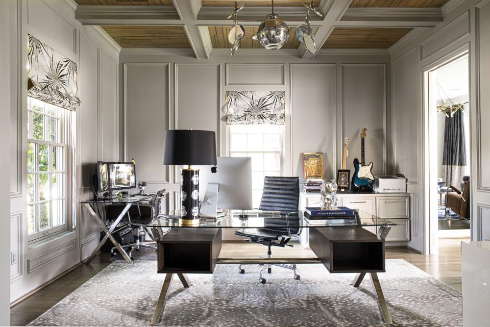 “I like to have everything subtly work together, so there is continuity, but no themes,” says Loya. “If I have one color in a room, I’m going to bring it into the next room, whether it’s a trim on a pillow or a lacquered wall. I believe continuity keeps a home feeling secure and warm.” The home office, which one enters from the living room through French doors, has coffered ceilings covered in Holland & Sherry wallpaper and Roman shades by Jim Thompson that Loya trimmed with gold-toned taffeta to reflect the metals of the adjacent living room. (The Antelope AX rug by Stark Carpet that she enhanced with a gold-bound stitch also complements the gold accents seen throughout the home.) The desk by High Fashion Home and chair from Design Within Reach are in keeping with the retro lighting fixture, which the owner found at a flea market. “It’s a vintage operating room light that we polished and fixed up,” Loya confides.