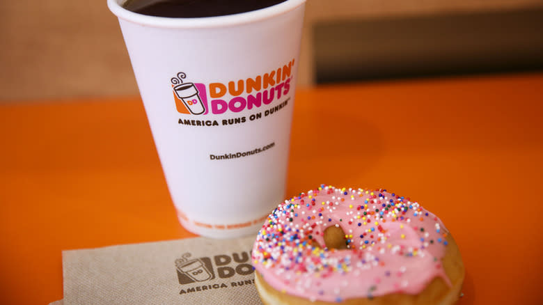 Dunkin' coffee and donut on orange table with napkin