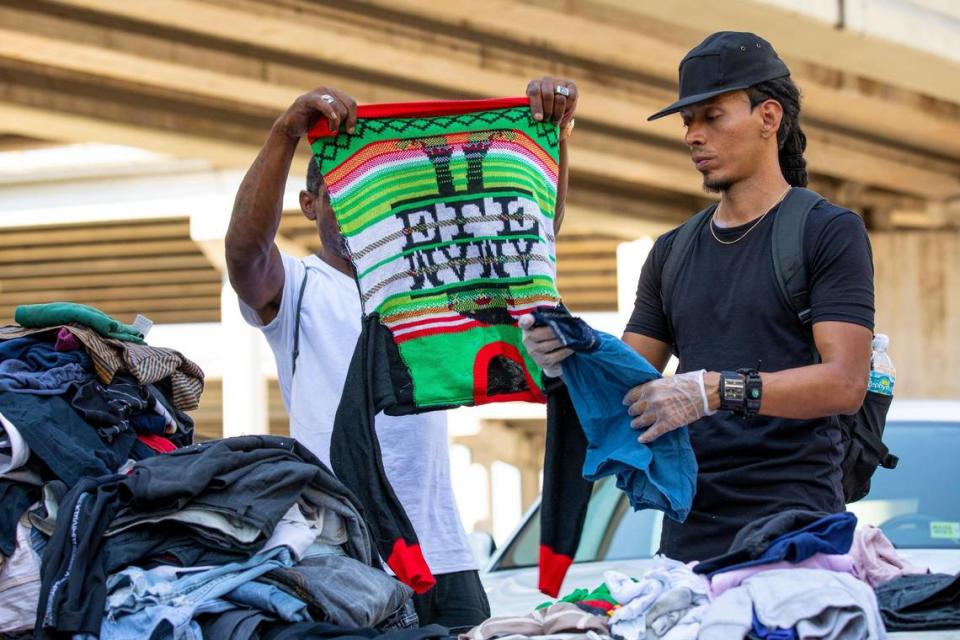 A Black Men Build member, right, and a homeless man help organize donated clothing during a donation and feeding event hosted by The Smile Trust, Inc. near Southwest 2nd Avenue and Second Street in Downtown Miami, Florida, on Sunday, October 17, 2021.