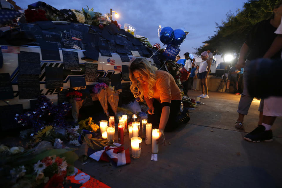 Tasha Lomoglio, of Dallas, lights candles at a makeshift memorial in honor of the slain Dallas police officers in front of police headquarters, in Dallas