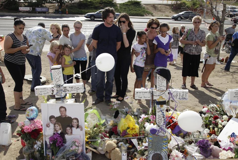 Actor Christian Bale, center, left, and his wife Sibi Blazic visit a memorial to the victims of Friday's mass shooting, Tuesday, July 24, 2012, in Aurora, Colo. Twelve people were killed when a gunman opened fire during a late-night showing of the movie "The Dark Knight Rises," which stars Bale as Batman. (AP Photo/Ted S. Warren)