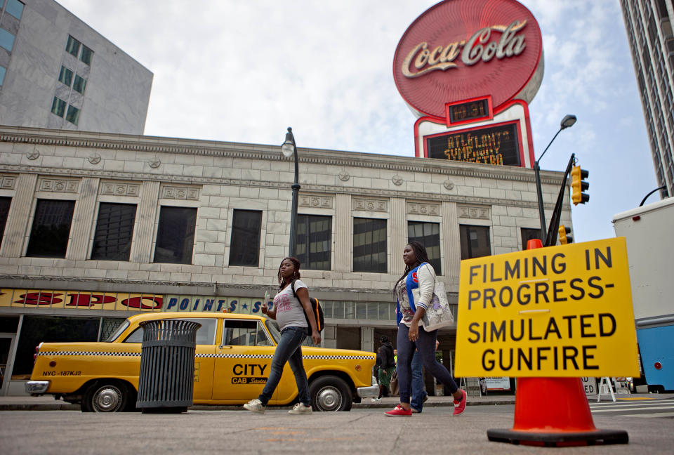 A sign warns people of simulated gunfire around downtown Peachtree Street during filming for the movie "Anchorman: The Legend Continues," Friday, May 10, 2013, in Atlanta. Peachtree Street was converted into a vintage New York City street scene, complete with New York taxi cabs and graffiti-painted walls. The film, a sequel to 2004's "Anchorman: The Legend of Ron Burgundy," is scheduled for release nationwide on Dec. 20, 2013. (AP Photo/David Goldman)