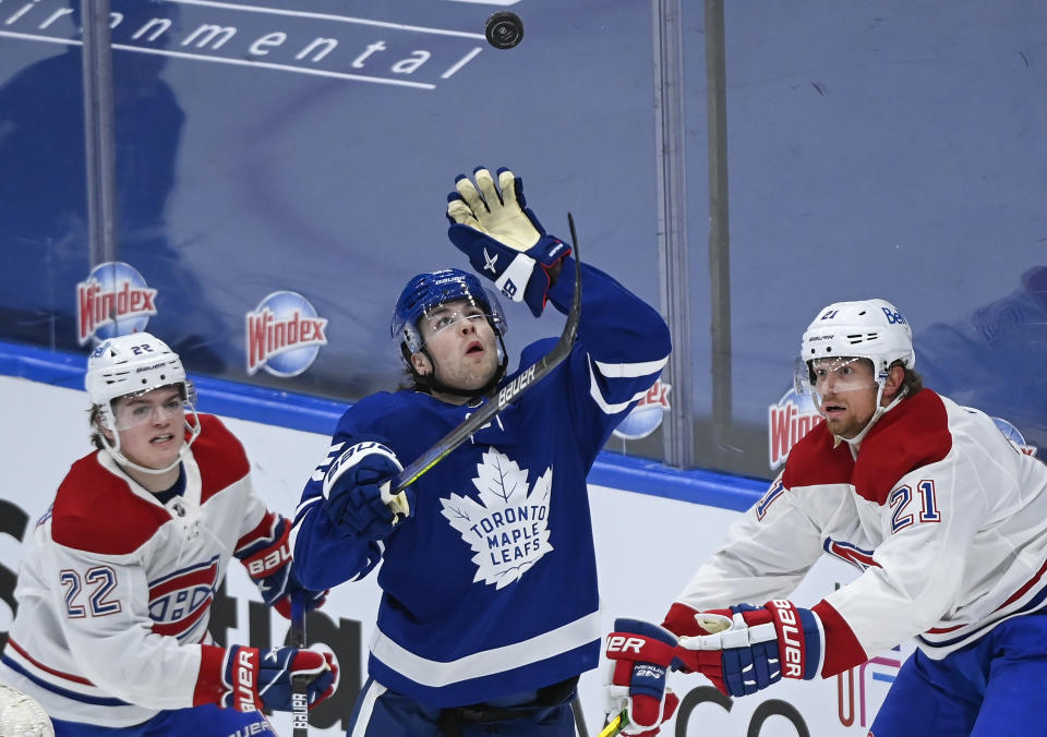 Toronto Maple Leafs defenseman Ben Hutton (55) gloves the puck as Montreal Canadiens forwards Cole Caufield (22) and Eric Staal (21) watch during the third period of an NHL hockey game Saturday, May 8, 2021, in Toronto. (Nathan Denette/The Canadian Press via AP)