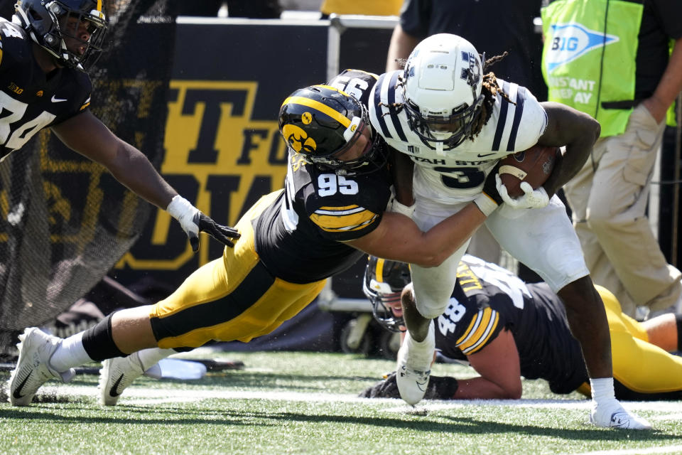 Utah State running back Rahsul Faison (3) tries to break a tackle by Iowa defensive lineman Aaron Graves (95) during the second half of an NCAA college football game, Saturday, Sept. 2, 2023, in Iowa City, Iowa. Iowa won 24-14. (AP Photo/Charlie Neibergall)