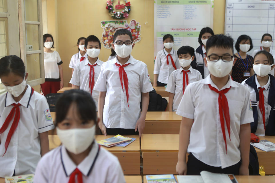 Teachers and students stand up for Vietnamese national anthem as they start a new week in Dinh Cong secondary school in Hanoi, Vietnam Monday, May 4, 2020. Students across Vietnam return to school after three months of studying online due to school closure to contain the spread of COVID-19. (AP Photo/Hau Dinh)