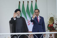 Iran's President Ebrahim Raisi, left, and Indonesian President Joko Widodo, right, wave to journalists during their meeting at the Presidential Palace in Bogor, West Java, Indonesia, Tuesday, May 23, 2023. (AP Photo/Achmad Ibrahim)