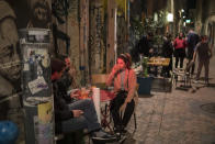 Friends share a drink at a bar before curfew in Marseille, southern France, Sat, Oct. 24, 2020. The curfew imposed in eight regions of France last week, including Paris and its suburbs, is being extended to 38 more regions and Polynesia. (AP Photo/Daniel Cole)